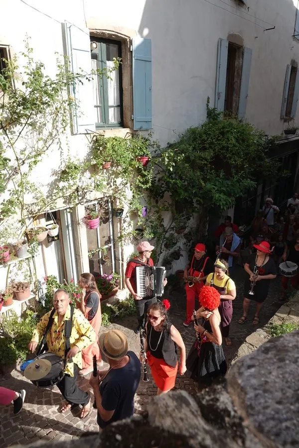 La fanfare descend une ruelle fleurie d'Olargues